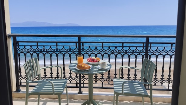 A balcony with a table set for breakfast, overlooking a beach and the sea. - Beachfront Panorama Aprtmnt - Kythira Seafront Gem (Kithira)