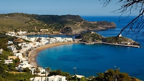 A coastal town with white buildings, a curved bay, and a small island with a lighthouse. - Beachfront Panorama Aprtmnt - Kythira Seafront Gem (Kithira)