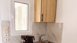 Eine kleine Küche mit integriertem Geschirrspüler, Spüle und Holzschränken.
