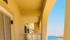 Ein Balkon mit Tisch und Stühlen, einem Kühlschrank und Meerblick.