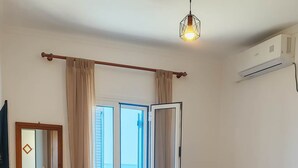Ein ordentlich eingerichtetes Schlafzimmer mit einem Bett, Nachttisch und einem Fenster mit Vorhängen.