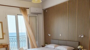 Une chambre d’hôtel avec un lit, des tables de chevet, un bureau et une vue sur la mer.