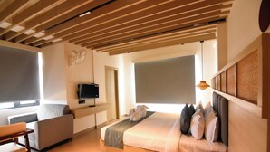 A modern hotel room with a large bed, a sofa, a TV, and a desk.