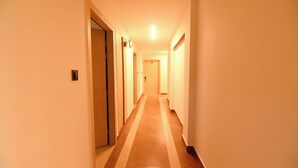A long, narrow hallway with a tiled floor and doors on both sides.