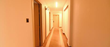 A long, narrow hallway with a tiled floor and doors on both sides.