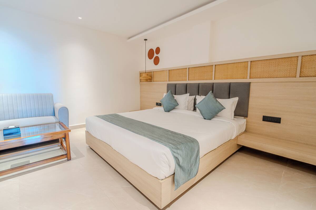 A modern bedroom with a large bed, a bedside table, and a sofa.