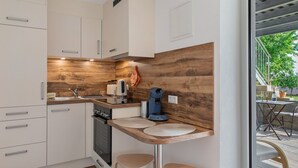 Eine moderne Küche mit weißen Schränken, einer Holzvertäfelung, einer Kaffeemaschine und zwei Barhocker.