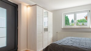 Ein Schlafzimmer mit Bett, Kleiderschrank, Fenster und Heizkörper.