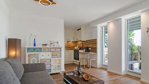 Ein modernes Wohnzimmer mit einer Couch, einem Couchtisch und einer Küche im Hintergrund.