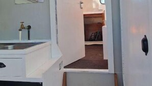 Un pasillo estrecho con tragaluces, una ventana pequeña y un banco de madera.