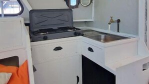 Una cocina compacta con estufa, lavamanos y un pequeño espejo.