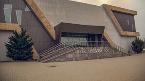 Un edificio moderno con un diseño angular distintivo, una escalera que conduce a la entrada y el nombre