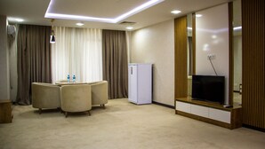 Una habitación de hotel con zona de estar, televisión y minibar.