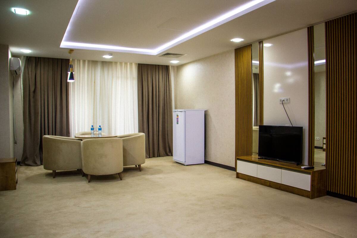 A hotel room with a seating area, a television, and a minibar.