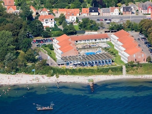 An aerial view of a coastal hotel with multiple buildings, a beach, and a pier.