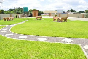 A well-maintained grassy area with picnic tables and a paved path. - Dream Catcher Hotel (Gaborone)