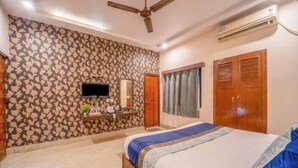Een slaapkamer met een bed, een televisie, een kledingkast, een plafondventilator en een airconditioning.