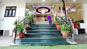 A staircase leading to a reception area with a modern ceiling design, potted plants, and a glass door entrance. - Hotel Ashok Palace Near Taj Mahal  Agra (Agra)