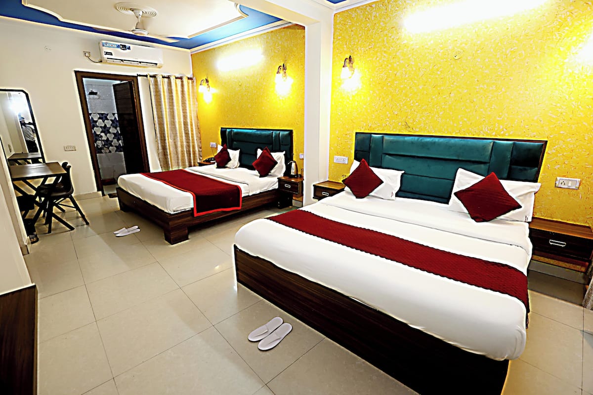 A hotel room with two beds, a desk, and a mirror.