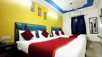 A hotel room with a large bed, two bedside tables, a ceiling fan, an air conditioning unit, and a mirror on the wall.