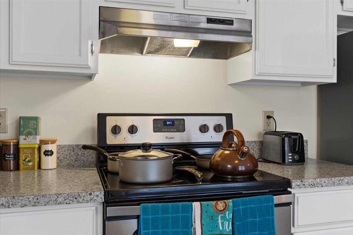 La cuisine est équipée d’une cuisinière Whirlpool, d’une bouilloire et d’un grille-pain. On y trouve également des bocaux de thé et d’épices sur le plan de travail.