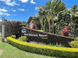 A sign for Maui Eldorado Resort with a stone wall and tropical landscaping.