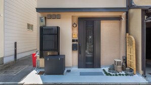 Ingresso di un edificio con una porta scura, una cassetta delle lettere e una telecamera di sicurezza.