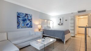 Une chambre d’hôtel moderne avec un lit, un canapé, une table basse en verre et un tableau au mur.