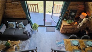 Een knus chaletinterieur met een bank, een eettafel en een trap naar een balkon.