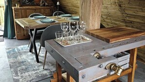 Een rustieke eetruimte met een houten tafel gedekt voor een maaltijd, een kroonluchter en een ingelijst beeld aan de muur.