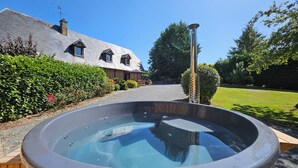 Un jacuzzi en un recinto de madera con una casa al fondo.