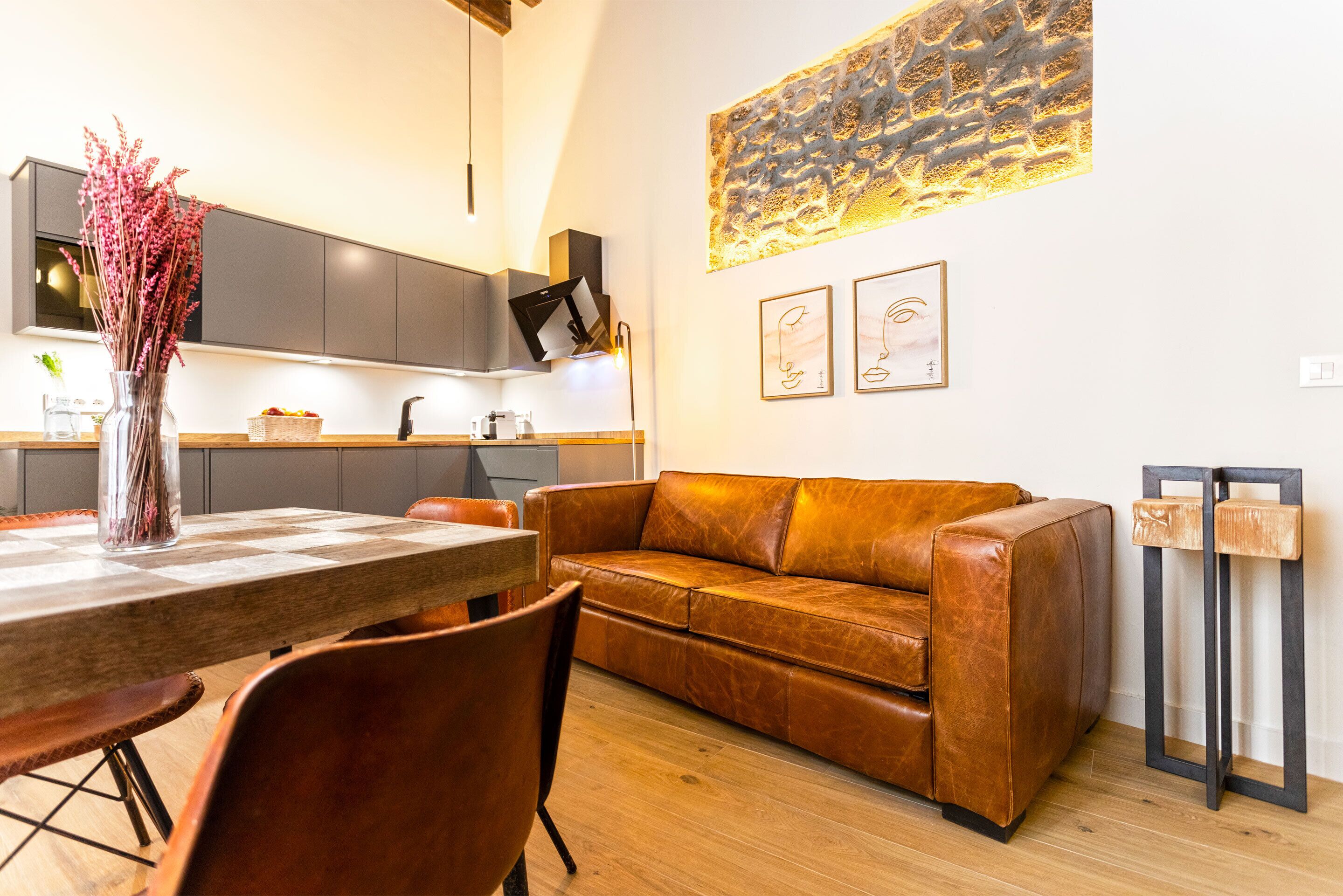 Une cuisine moderne avec un coin repas, comprenant un canapé en cuir, une table en bois et des chaises.