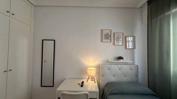 Un dormitorio con cama, mesita de noche, lámpara, espejo y cuadros en la pared.