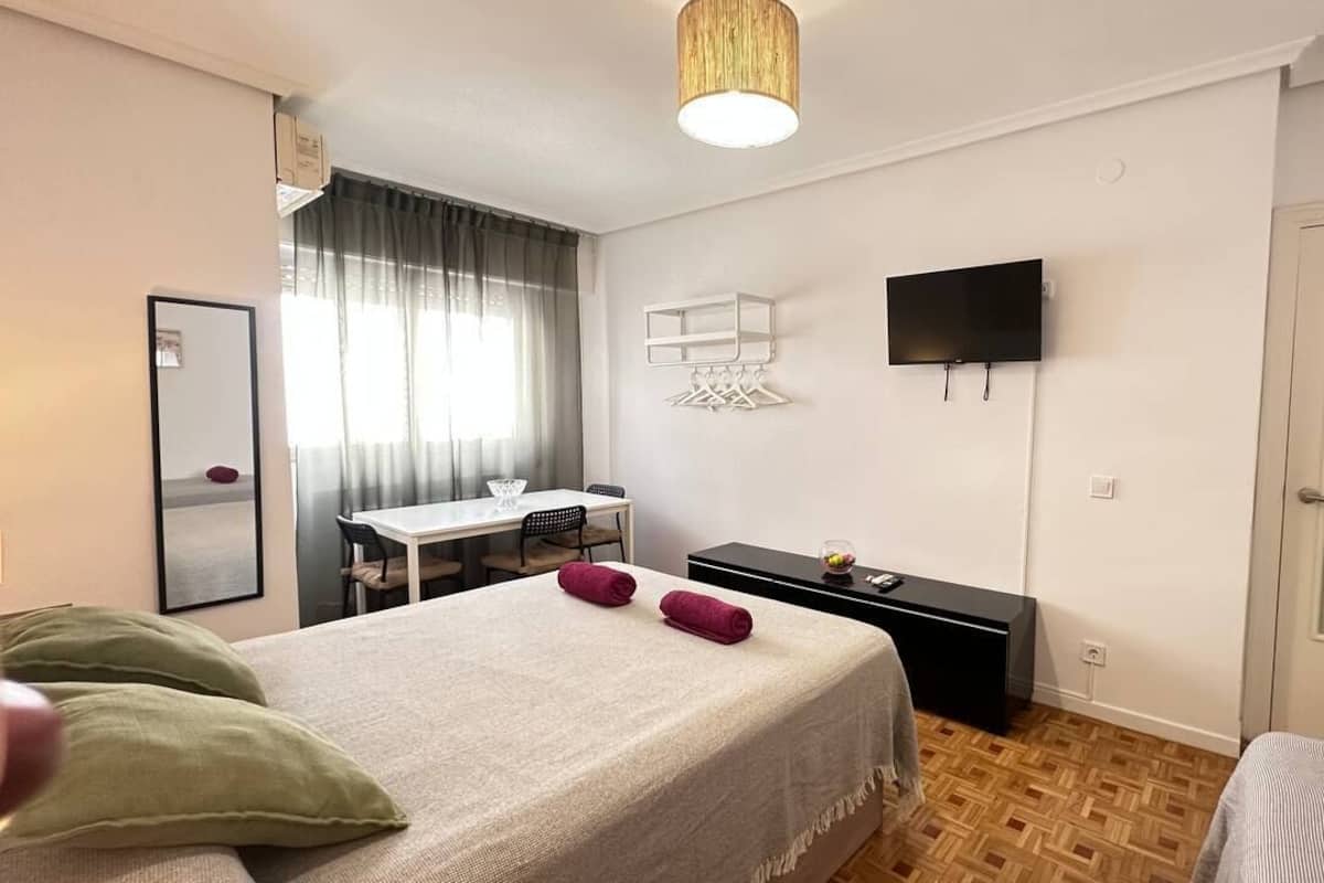 Ein Hotelzimmer mit Bett, Schreibtisch, Stuhl, Fernseher und Kleiderschrank.