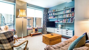 Ein modernes Wohnzimmer mit einer Couch, einem Sessel, einem Couchtisch und einem Bücherregal voller Bücher.