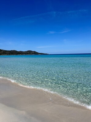 A beach with clear water, a sandy shore, and distant hills. - Room 'Chambre 1 - 1er Étage' with Mountain View, Wi-Fi and Air Conditioning (Murato)