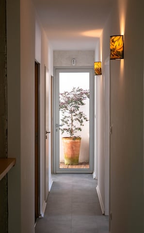 A hallway with a potted plant, a door, and a wall-mounted light fixture. - Villa 'Face Au Mont Bouquet' with Private Pool, Wi-Fi and Air Conditioning (Servas)