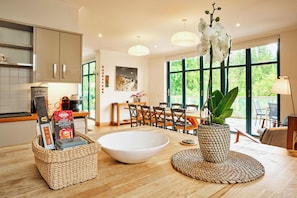 A modern kitchen with a large island, a dining area with a view, and a living space with a large window.