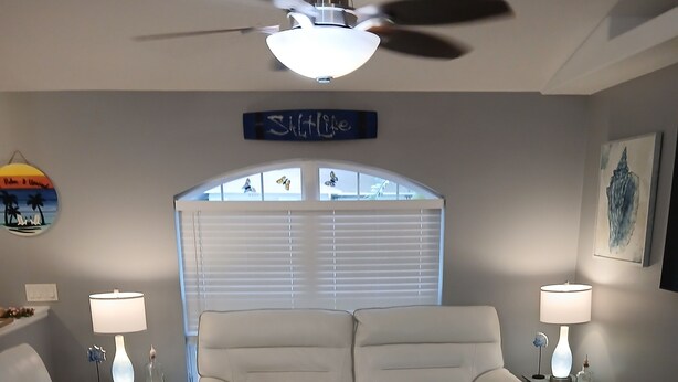 A living room with a beige sectional sofa, two side tables with lamps, a ceiling fan, and a large window with blinds. - Clean 3/2 fully furnished house in Homosassa. Close to river with many extras (Homosassa)