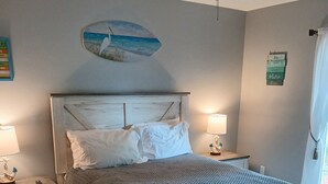 A bedroom with a wooden bed, two bedside tables with lamps, a ceiling fan, and a wall decoration. - Clean 3/2 fully furnished house in Homosassa. Close to river with many extras (Homosassa)