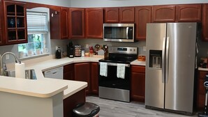 A modern kitchen with wooden cabinets, stainless steel appliances, and a central island. - Clean 3/2 fully furnished house in Homosassa. Close to river with many extras (Homosassa)