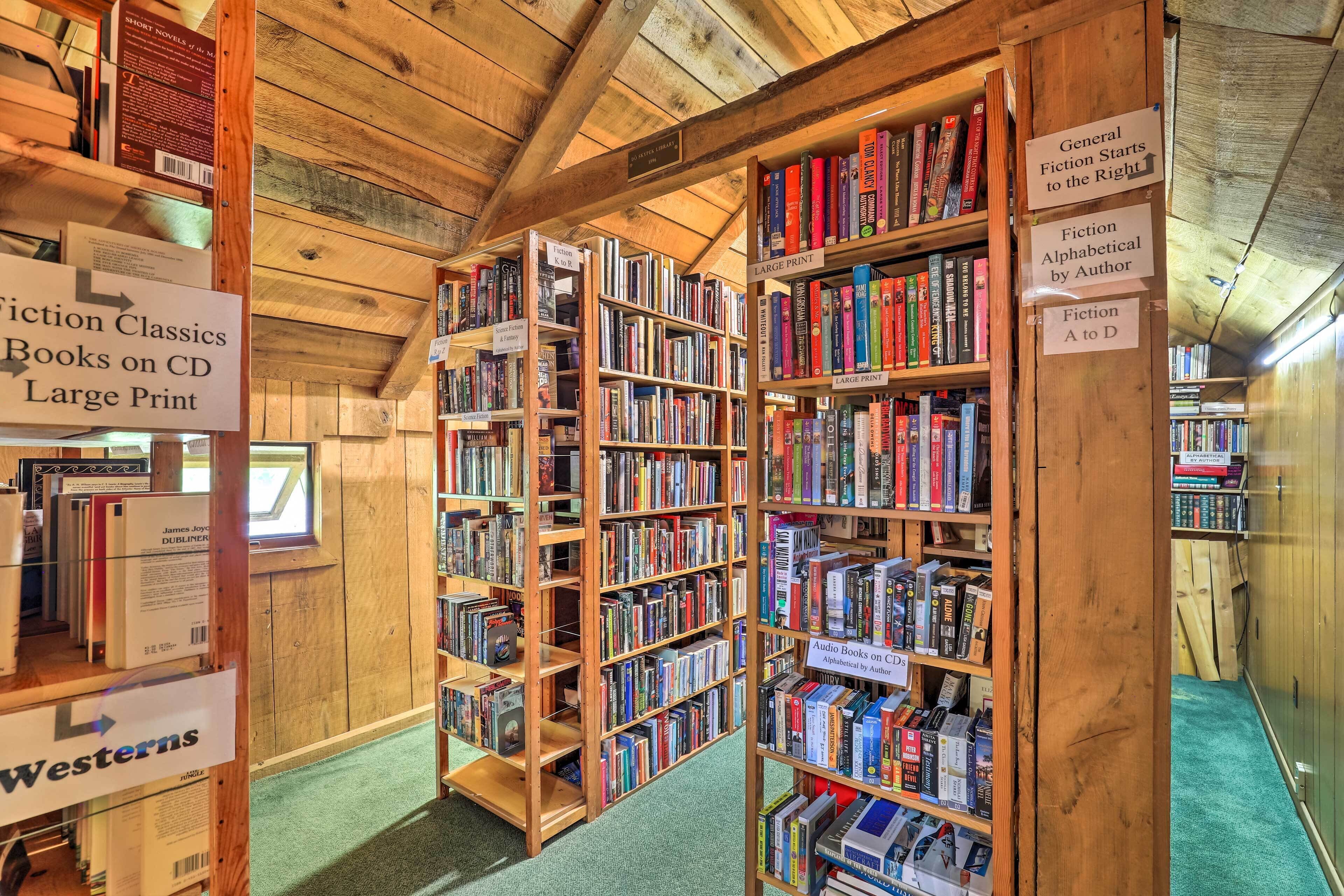 Una biblioteca con estanterías señalizadas para clásicos de ficción, libros de gran formato y audiolibros.
