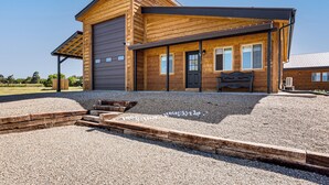 Een houten gebouw met twee verdiepingen, een garage, een overdekte veranda en een grindpad.