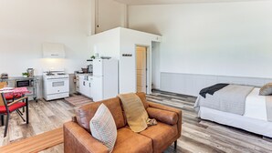 Een knus woongedeelte met een kitchenette, een slaapbank en een bed.