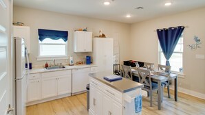 A modern kitchen with white cabinetry, a built-in dishwasher, and a dining area with a table and chairs. - 4 Mi to Rockport Beach Park: Home w/ Resort Perks (Rockport)