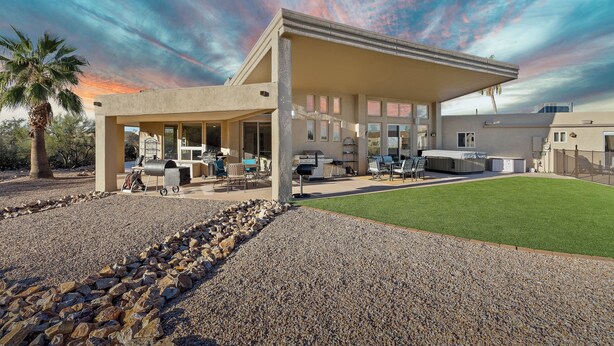 Een modern huis met een overdekte patio, terrasmeubilair buiten en een verzorgd gazon.