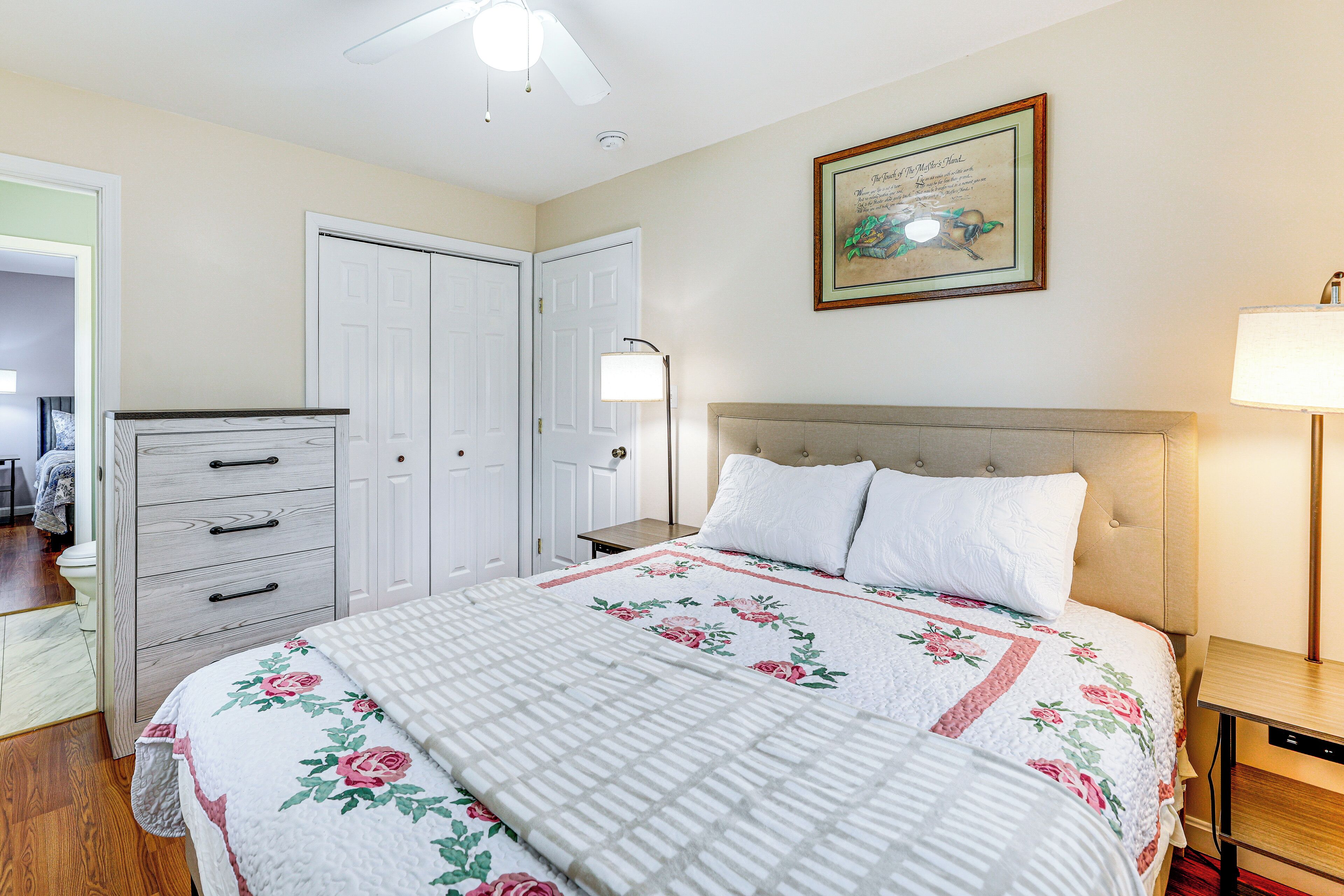 Ein Schlafzimmer mit Bett, Kommode, Nachttisch und Deckenventilator.