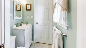A bathroom with a white toilet, a sink with a mirror above it, and a towel hanging on a rack.