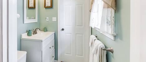 A bathroom with a white toilet, a sink with a mirror above it, and a towel hanging on a rack.