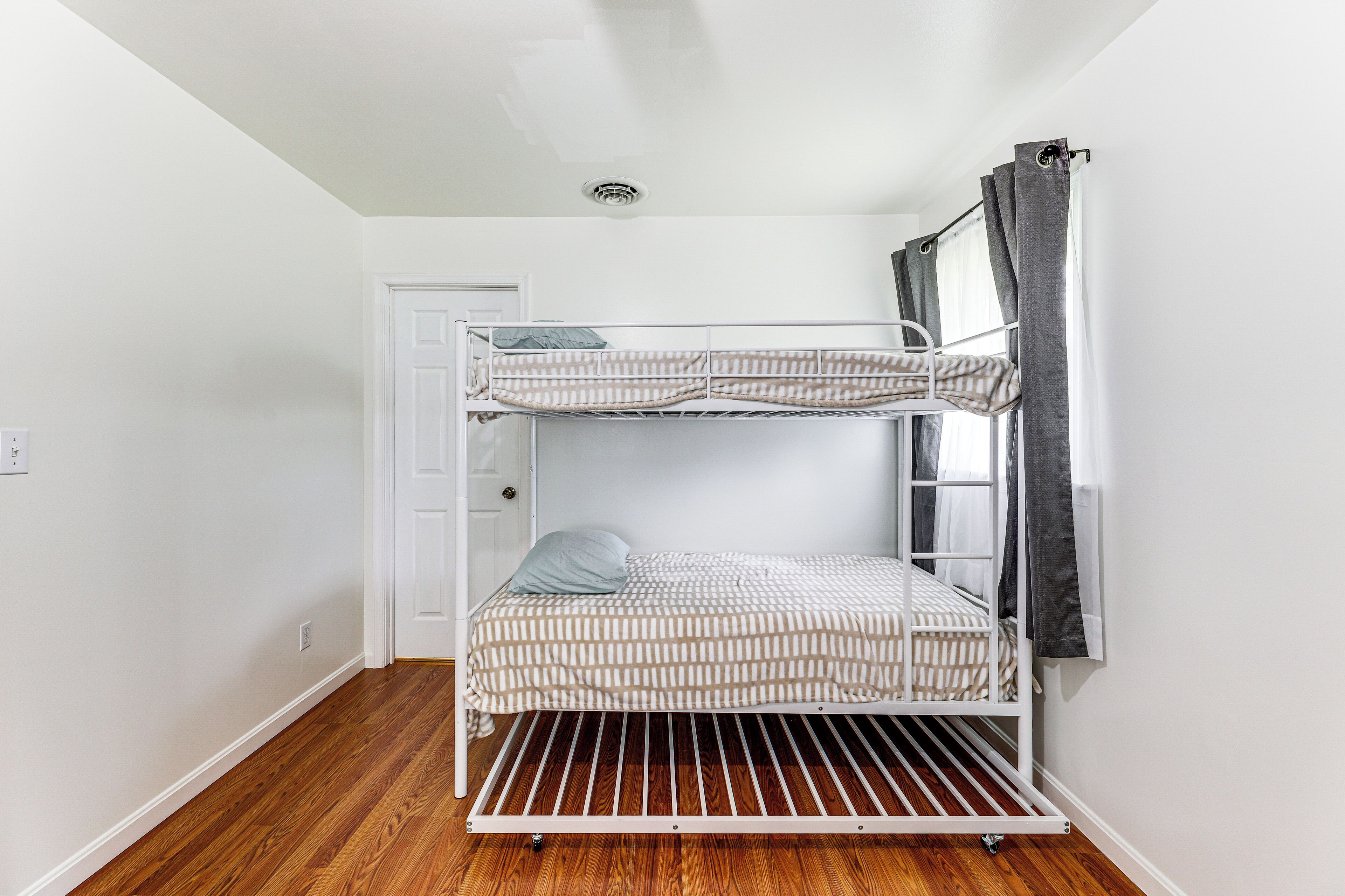 Una cama litera en una habitación con paredes blancas y suelo de madera.